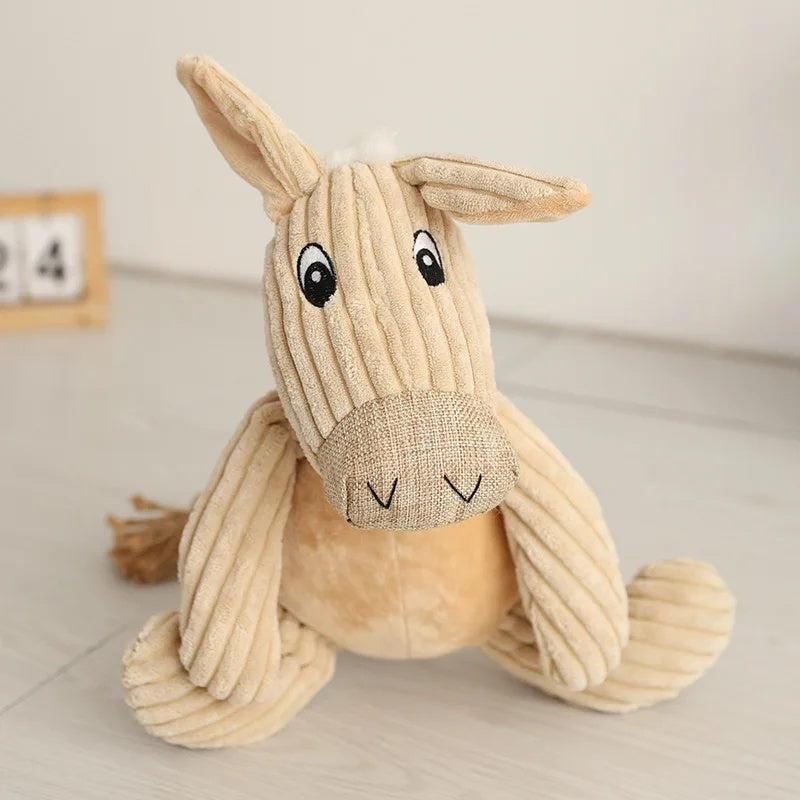 Cute beige corduroy donkey plush dog toy sitting upright on a light wooden floor.