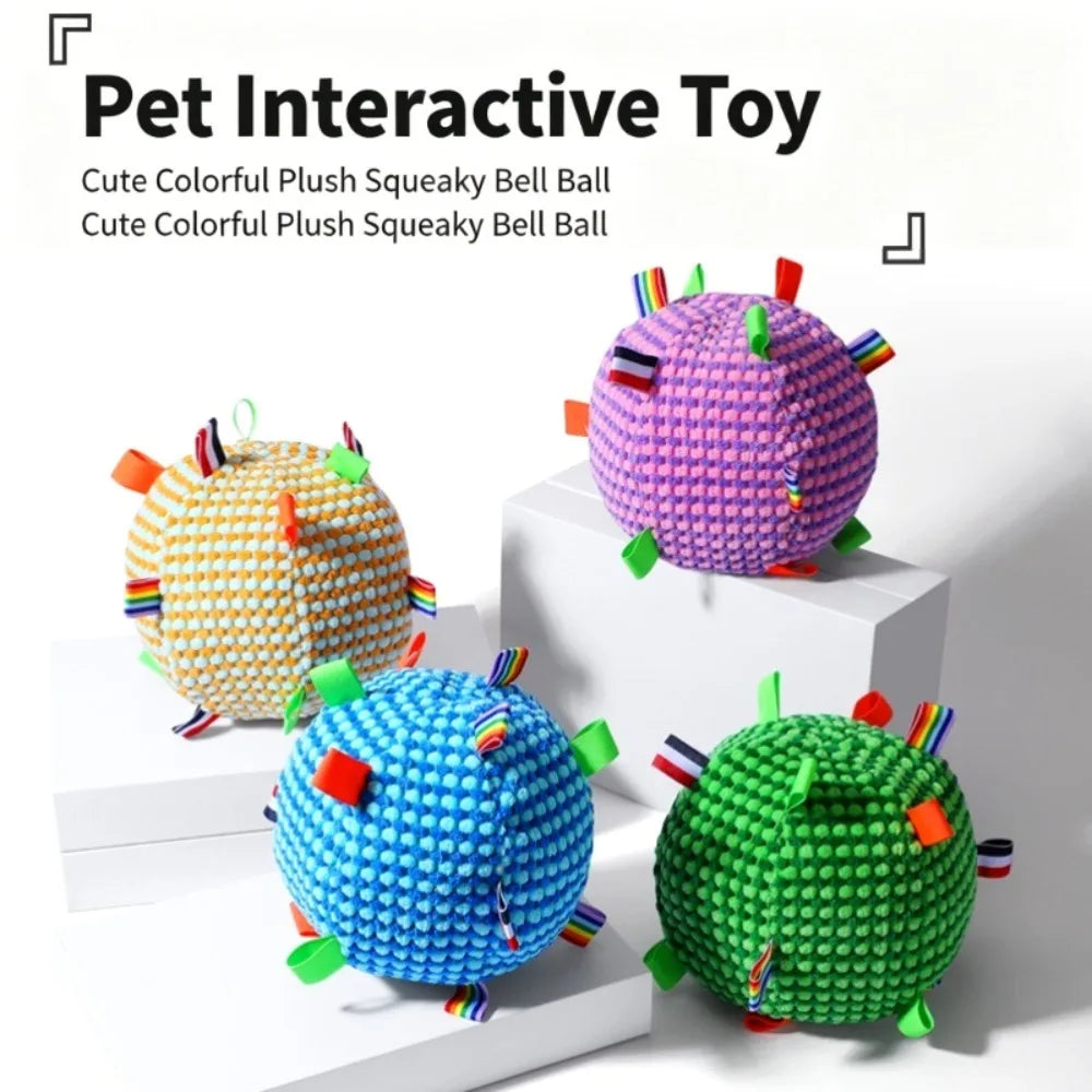 Four colorful plush squeaky toy balls in yellow, purple, blue, and green with rainbow tags on display stands.